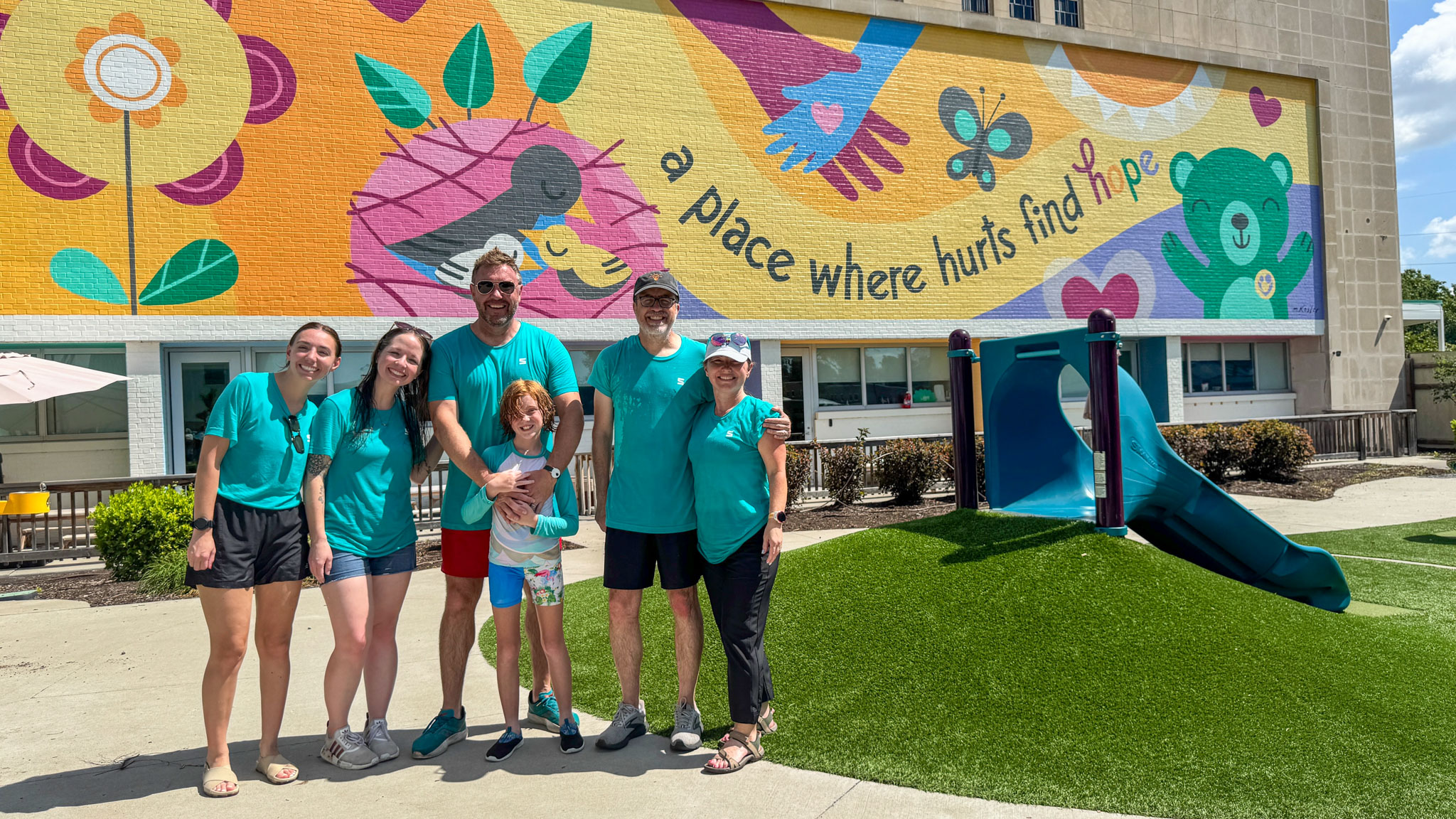 The SLATTERY team standing outside in the play area with colorful mural in the background
